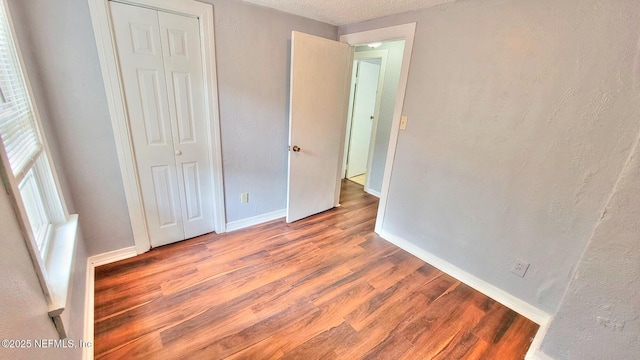 unfurnished bedroom featuring light hardwood / wood-style floors, a closet, and a textured ceiling