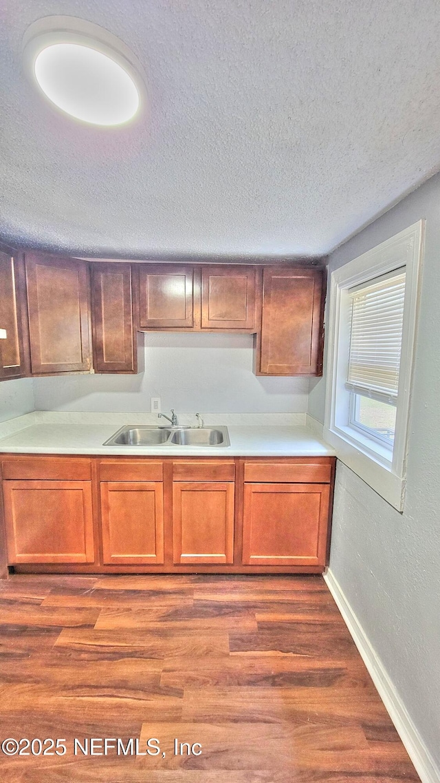 kitchen featuring wood-type flooring, sink, and a textured ceiling