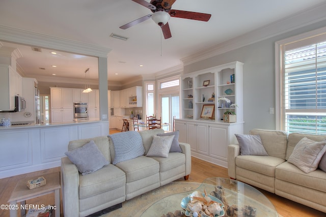 living room with ceiling fan, ornamental molding, and light hardwood / wood-style floors