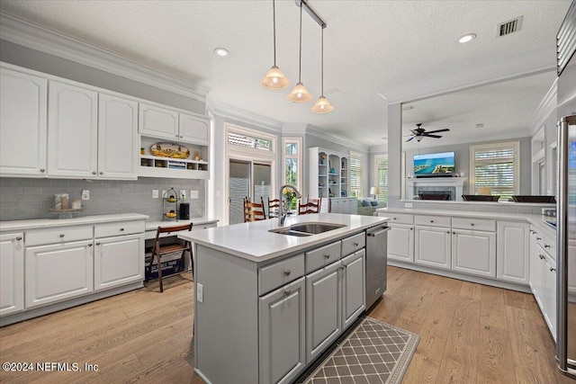 kitchen with pendant lighting, sink, white cabinetry, a textured ceiling, and a center island with sink