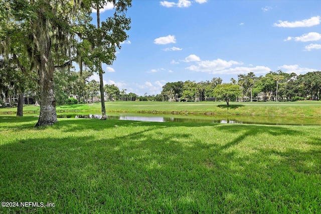 surrounding community with a water view and a yard