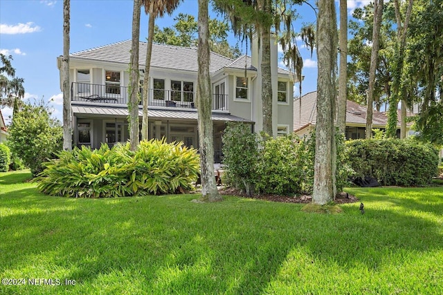 rear view of house with a lawn and a balcony