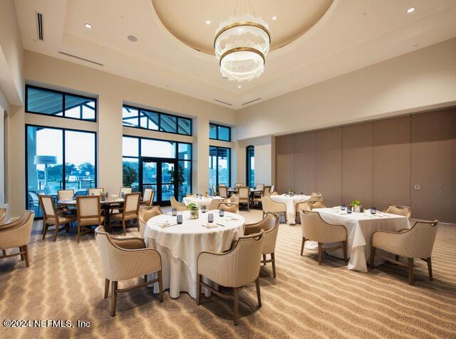 dining room featuring a tray ceiling, a chandelier, light carpet, and a high ceiling