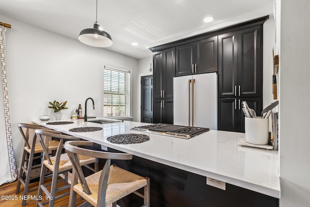 kitchen with a breakfast bar, high end refrigerator, hanging light fixtures, hardwood / wood-style flooring, and stainless steel gas stovetop