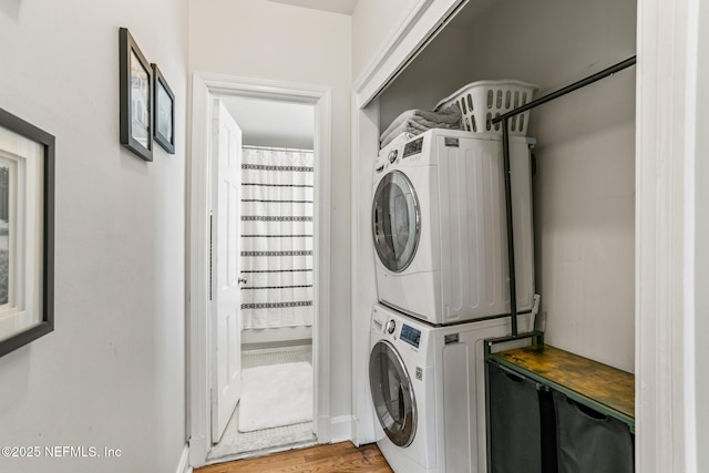 clothes washing area featuring wood-type flooring and stacked washer and clothes dryer