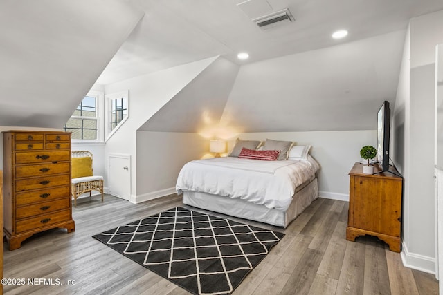 bedroom with vaulted ceiling and light wood-type flooring