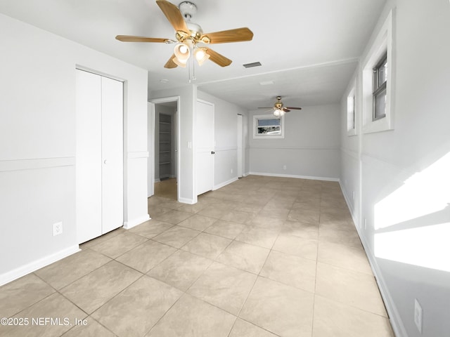 unfurnished bedroom with light tile patterned floors, ceiling fan, and a closet