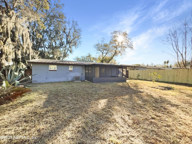 back of property featuring a sunroom, a lawn, and central air condition unit