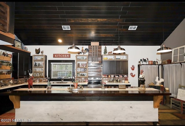 kitchen with stainless steel electric range, sink, a breakfast bar area, and decorative light fixtures