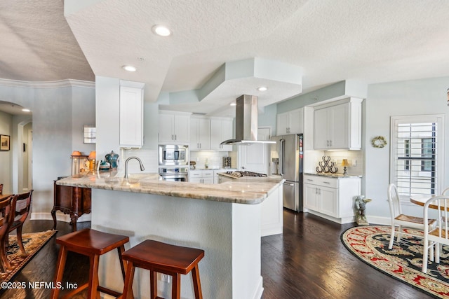 kitchen with white cabinetry, island exhaust hood, appliances with stainless steel finishes, and light stone counters