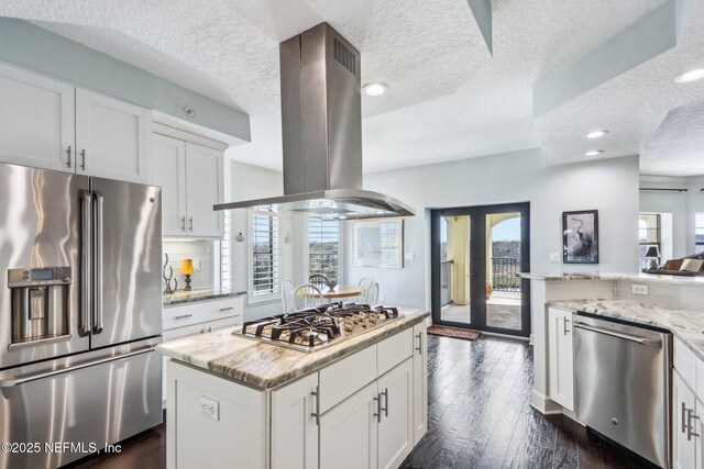 kitchen featuring white cabinetry, island exhaust hood, appliances with stainless steel finishes, and light stone countertops