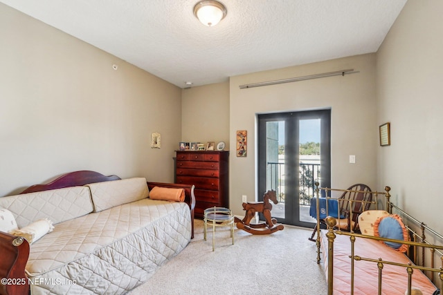 bedroom with access to exterior, light carpet, and a textured ceiling