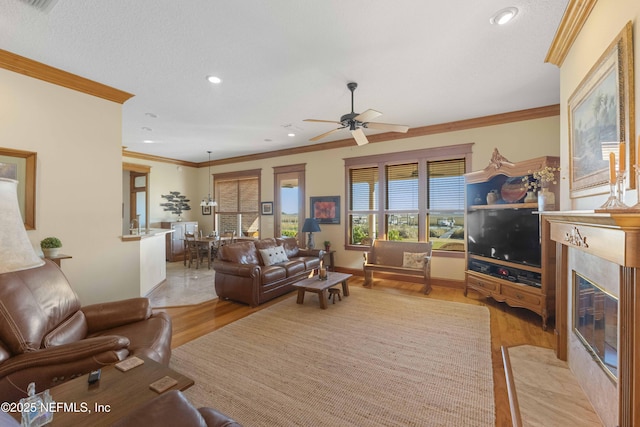 living room featuring a premium fireplace, ornamental molding, ceiling fan, and light hardwood / wood-style floors