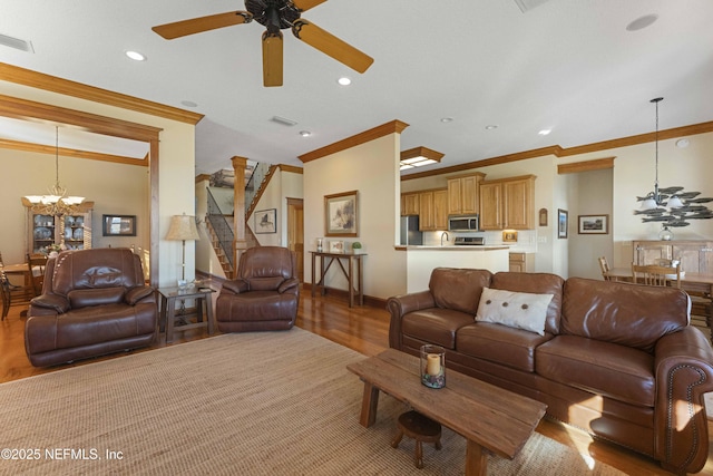 living room with crown molding, ceiling fan with notable chandelier, and light hardwood / wood-style flooring