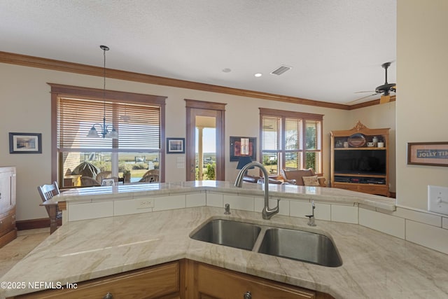 kitchen with sink, crown molding, decorative light fixtures, kitchen peninsula, and ceiling fan