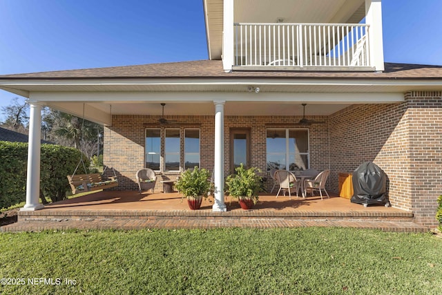 rear view of house featuring a balcony, a yard, and a patio area