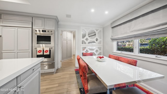 kitchen featuring gray cabinetry, ornamental molding, light hardwood / wood-style floors, and stainless steel double oven