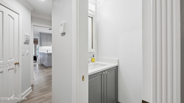 bathroom featuring tasteful backsplash, wood-type flooring, crown molding, and vanity