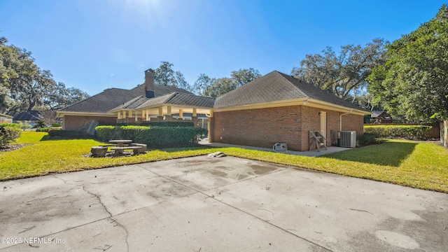 view of side of home with a lawn, central air condition unit, and a patio area