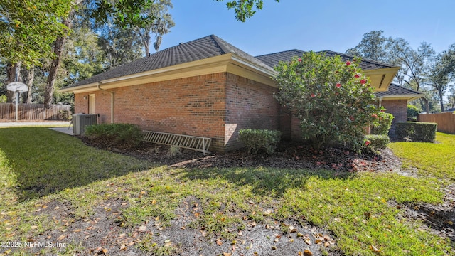 view of side of property with a yard and central AC