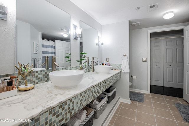 bathroom featuring tasteful backsplash, vanity, tile patterned flooring, and toilet