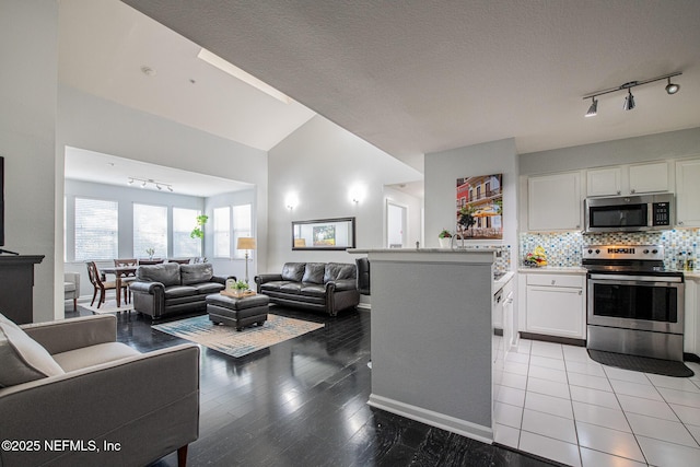 kitchen featuring lofted ceiling, white cabinetry, light wood-type flooring, appliances with stainless steel finishes, and decorative backsplash