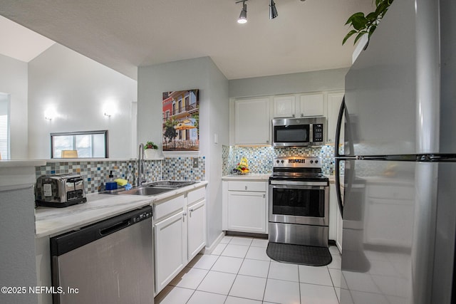 kitchen featuring sink, light tile patterned floors, white cabinets, stainless steel appliances, and backsplash