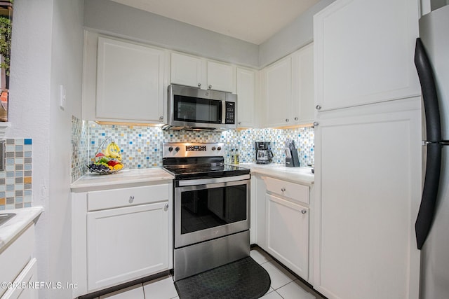 kitchen with stainless steel appliances, white cabinetry, light tile patterned floors, and decorative backsplash