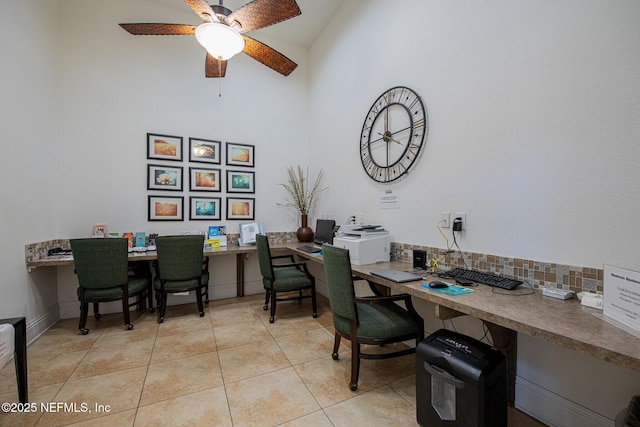 office with tile patterned flooring, a towering ceiling, built in desk, and ceiling fan