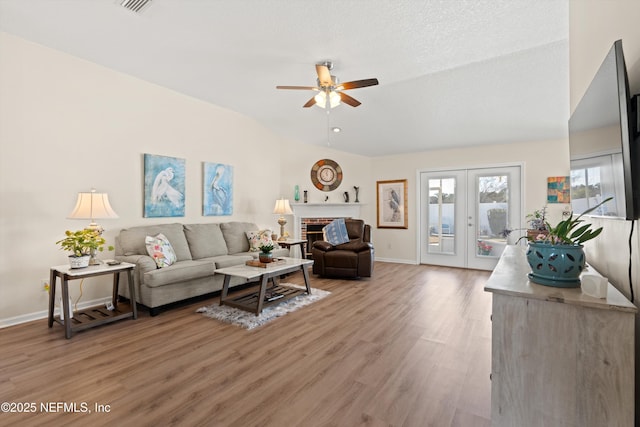 living room featuring a fireplace, wood-type flooring, ceiling fan, a textured ceiling, and french doors