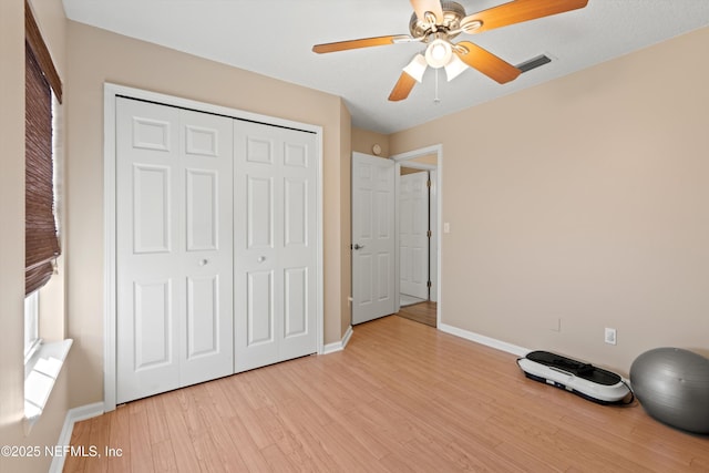 exercise room featuring ceiling fan and light hardwood / wood-style flooring