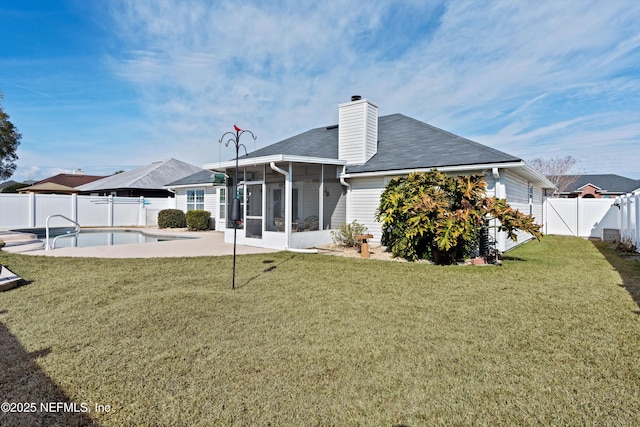 rear view of property with a patio, a yard, a fenced in pool, and a sunroom