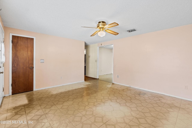 empty room with ceiling fan and a textured ceiling