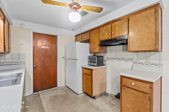 kitchen featuring sink, tasteful backsplash, a textured ceiling, white fridge, and ceiling fan