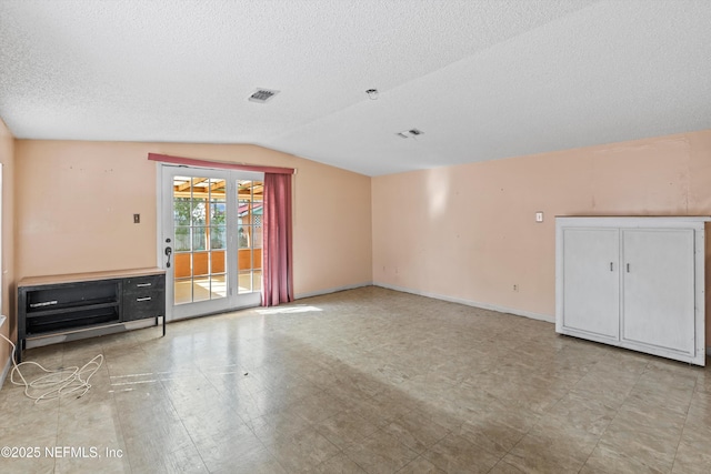 unfurnished living room featuring vaulted ceiling and a textured ceiling