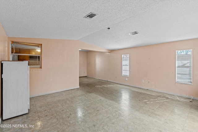 empty room with lofted ceiling and a textured ceiling