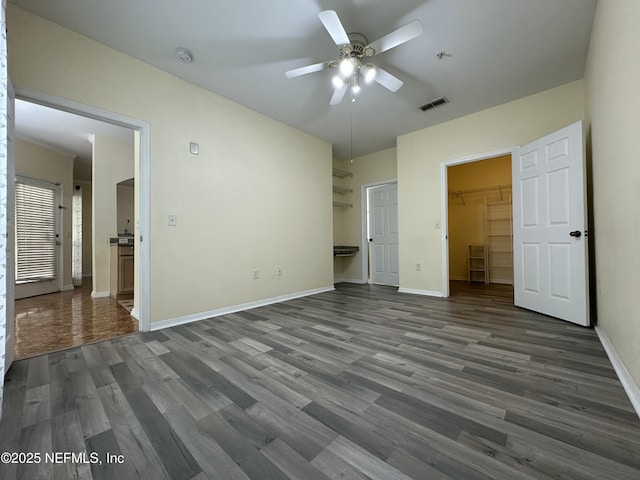 unfurnished bedroom featuring a walk in closet, dark hardwood / wood-style floors, ceiling fan, and a closet