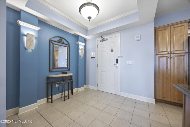 entrance foyer featuring ornamental molding, light tile patterned floors, and a tray ceiling