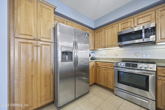 kitchen featuring tasteful backsplash, light tile patterned floors, and stainless steel appliances