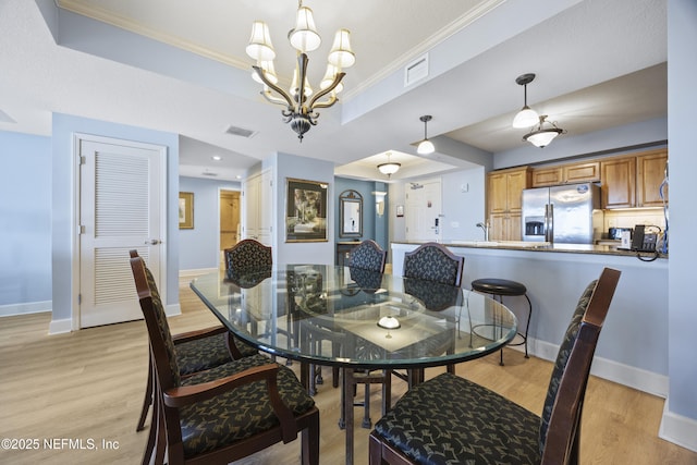 dining area featuring a raised ceiling, crown molding, and light wood-type flooring