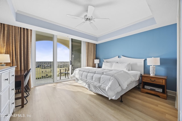 bedroom with light wood-type flooring, access to outside, ceiling fan, and a tray ceiling