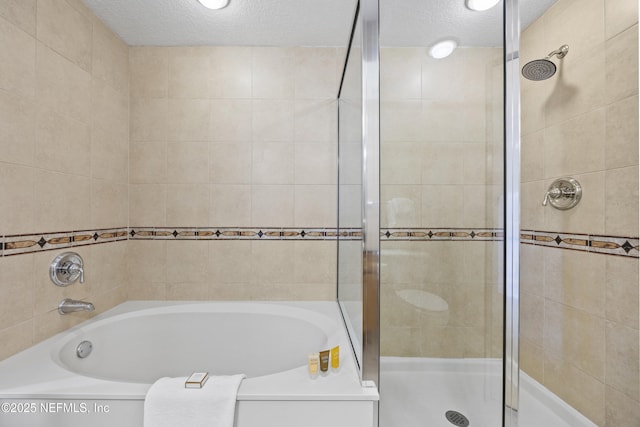 bathroom featuring shower with separate bathtub and a textured ceiling