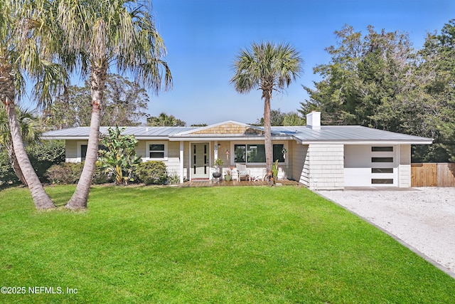 ranch-style home featuring a garage, covered porch, a front lawn, and solar panels