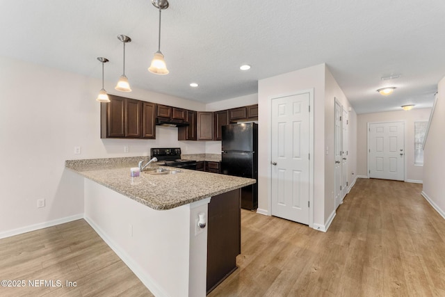 kitchen featuring dark brown cabinetry, sink, decorative light fixtures, kitchen peninsula, and black appliances