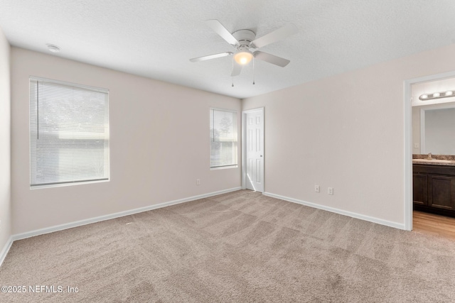 empty room with sink, light carpet, a textured ceiling, and ceiling fan