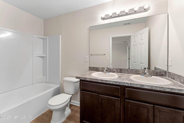 full bathroom with toilet, bathing tub / shower combination, wood-type flooring, a textured ceiling, and vanity