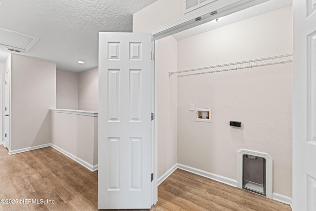 clothes washing area featuring hookup for a washing machine, a textured ceiling, and light hardwood / wood-style floors