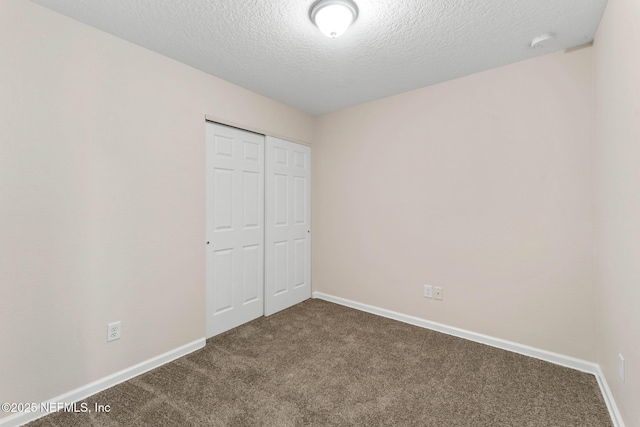 unfurnished bedroom with carpet flooring, a textured ceiling, and a closet