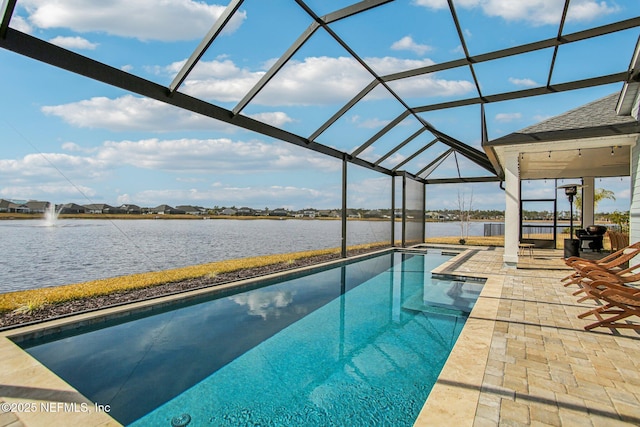 view of swimming pool featuring a patio area, a water view, and glass enclosure