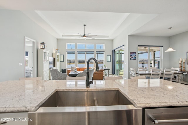 kitchen featuring a tray ceiling, sink, a wealth of natural light, and decorative light fixtures